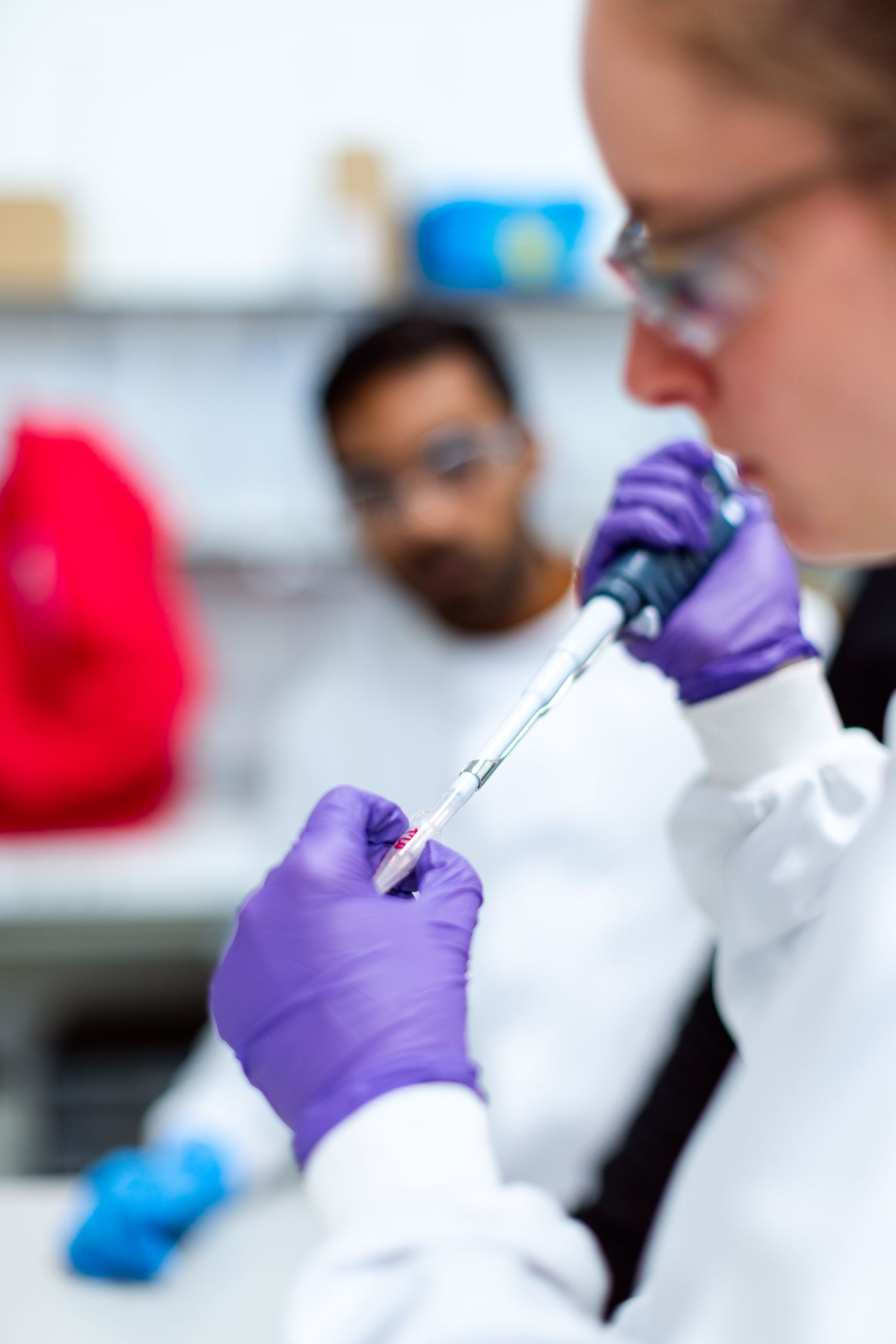 Stock photograph of researchers handling a sample with a pipette in a laboratory